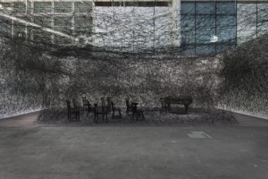 In Silence, 2002-2013 FILS DE LAINE NOIRE, PIANO À QUEUE ET CHAISES BRÛLÉS DIMENSIONS VARIABLES DIMENSIONS VARY VUE DE ART BASEL UNLIMITED 2013 © Chiharu Shiota. Photo Dirk Wetzel